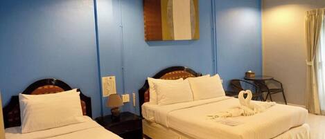A hotel room with two beds, a small table, a chair, and a painting on the wall.