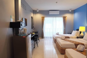 A hotel room with two beds, a desk, a chair, and a TV.