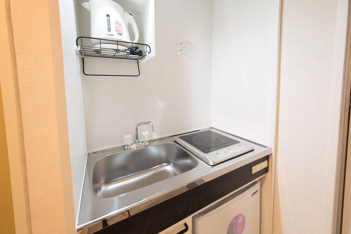 A compact kitchen with a sink, a built-in induction cooktop, and a small refrigerator.