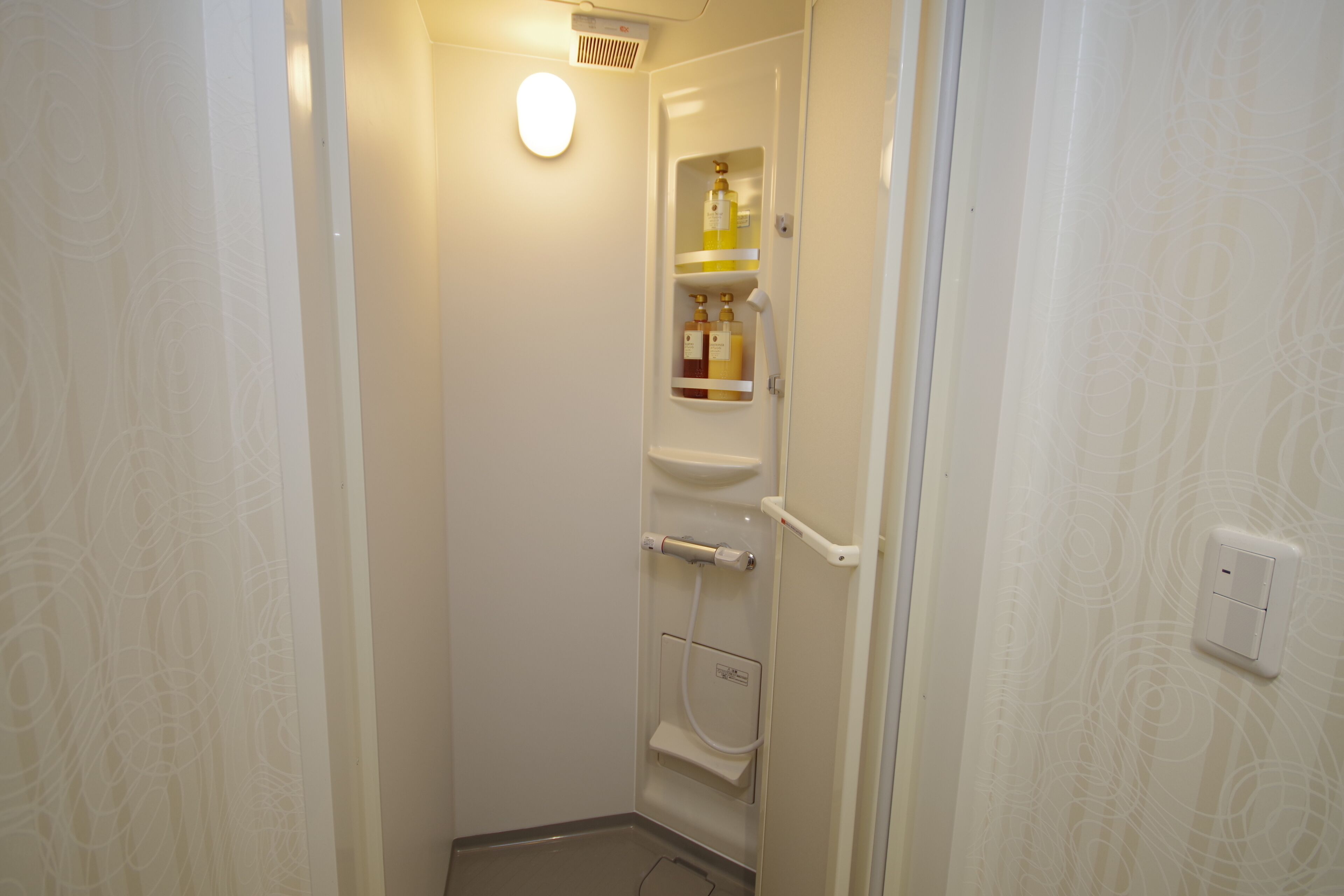 A small, narrow bathroom with a toilet, a sink, and a storage cabinet containing toiletries.