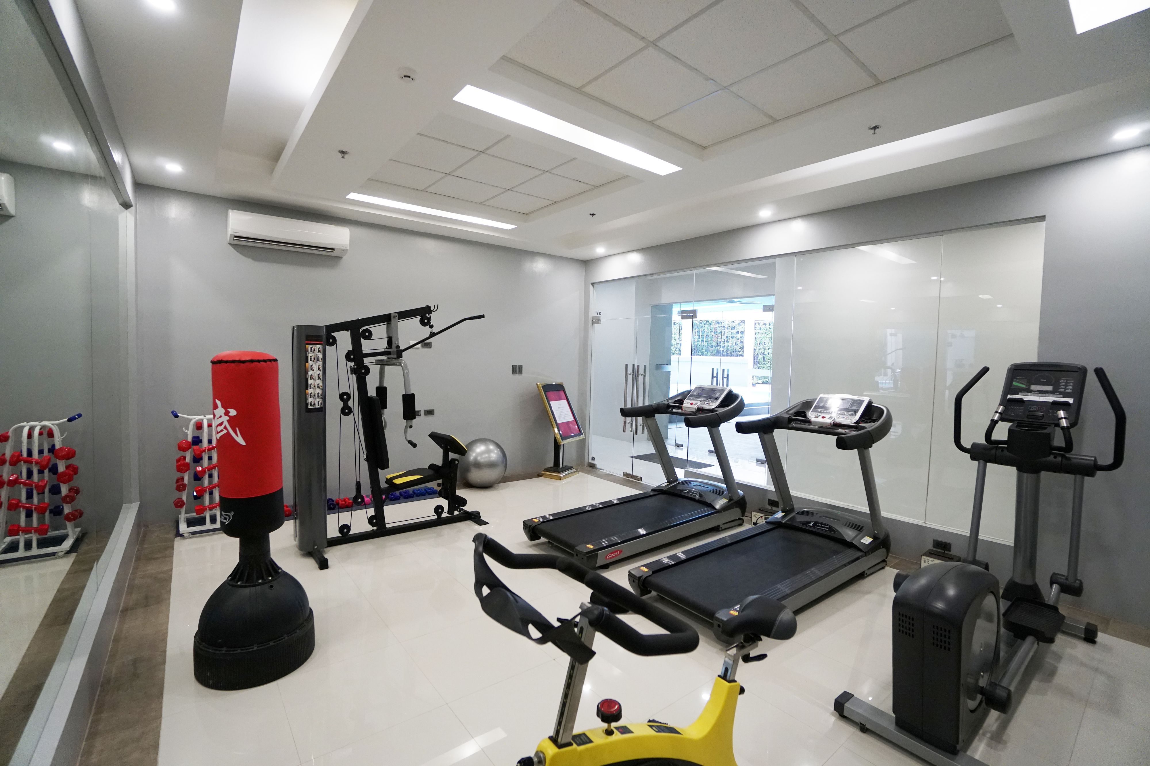 A gym with treadmills, a punching bag, weight machines, and a rowing machine.