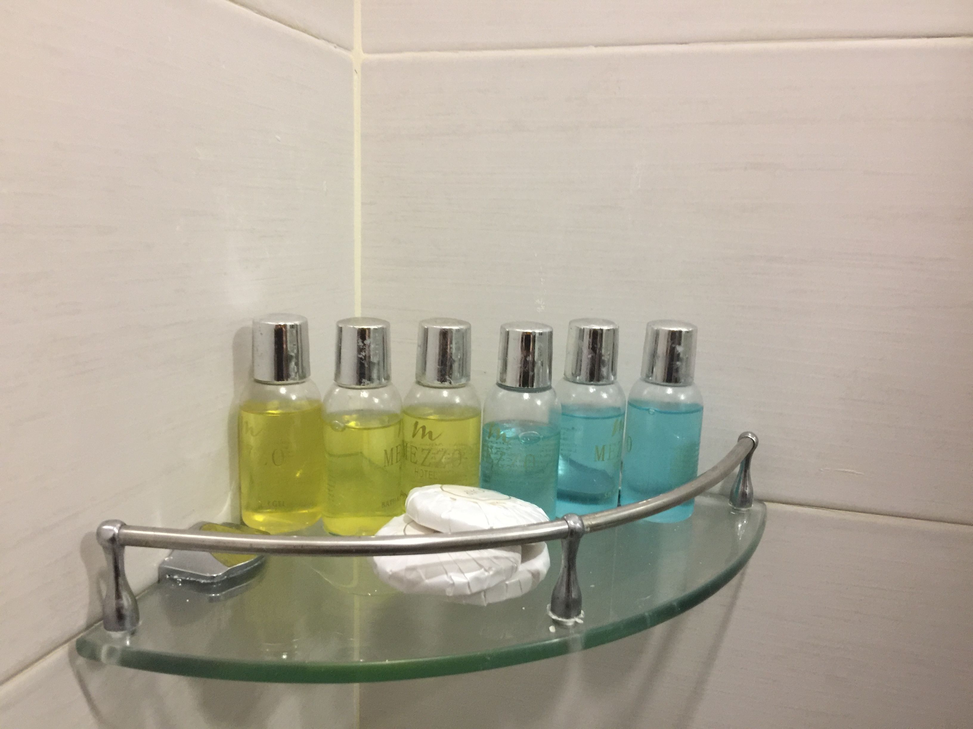 A glass shelf with toiletries in a bathroom.