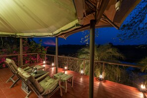 Eine Terrasse im Freien mit Holzmöbeln, einem Baldachin und Laternen.