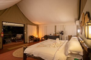 Ein Zeltraum mit einem Bett, zwei Stühlen, einem Tisch und einem Ventilator.
