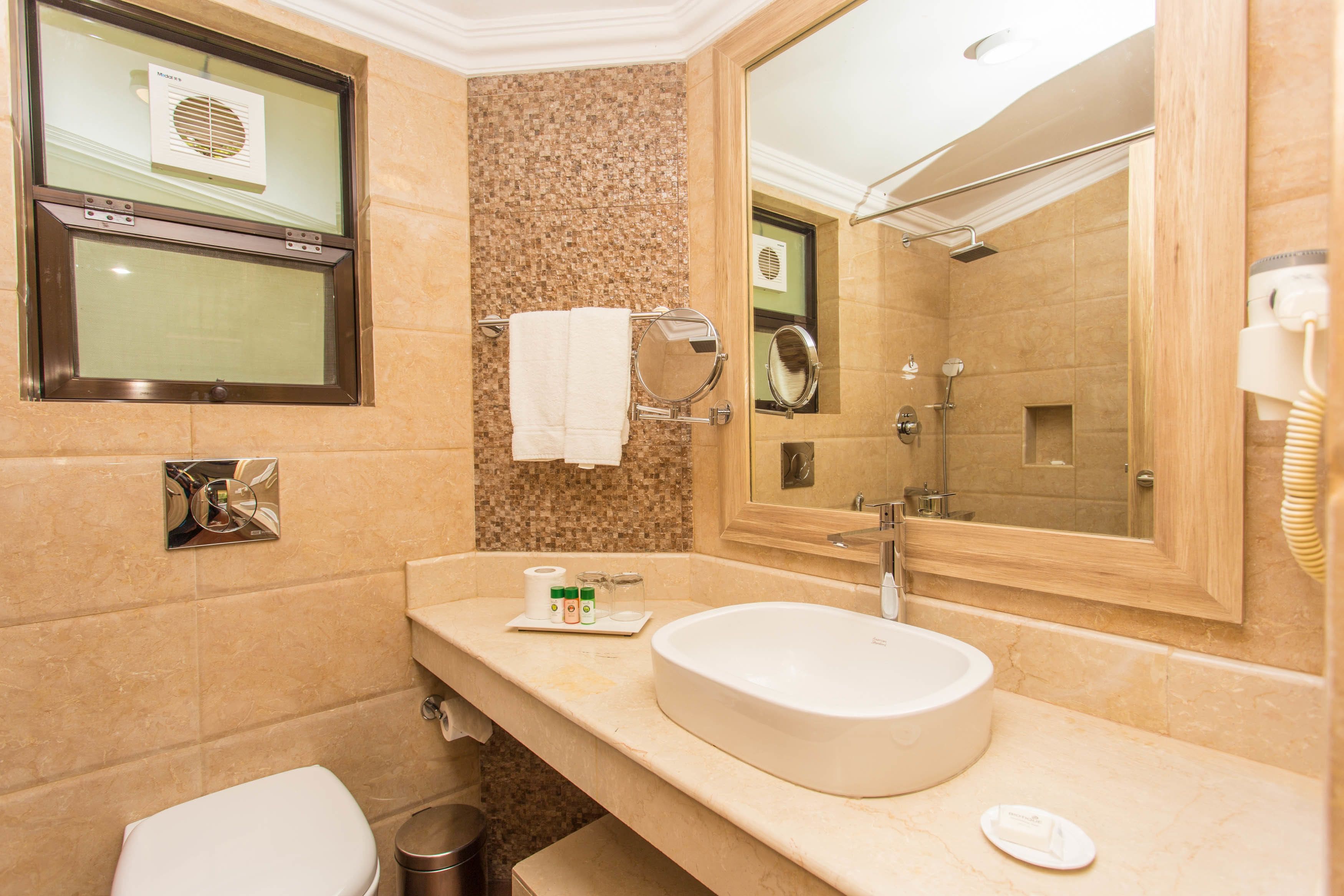 A bathroom with a large mirror, a sink, a toilet, and a shower.