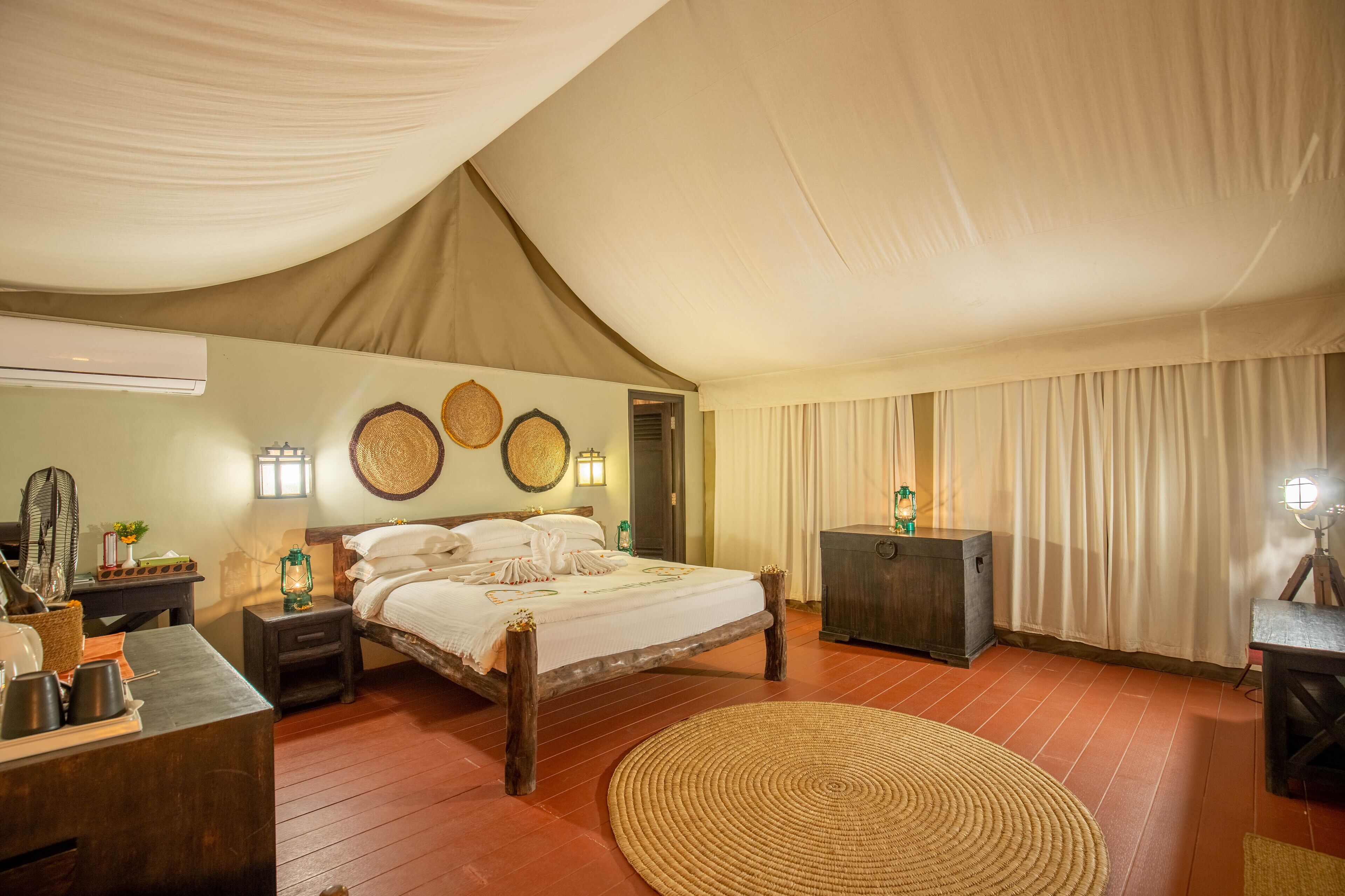 A room with a bed, bedside table, lamp, and a large woven rug.