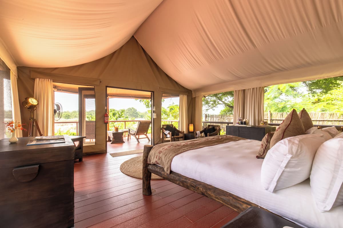 Una habitación con carpa, una cama, un escritorio de madera y sillas.