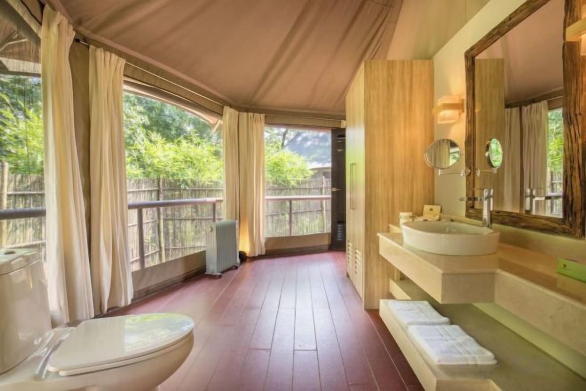 A bathroom with a toilet, sink, and large mirror.