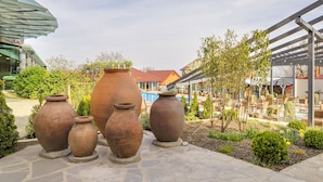 Terracotta pots arranged outdoors, a covered seating area, and a building with a red roof in the background. - Savaneti (Telavi)