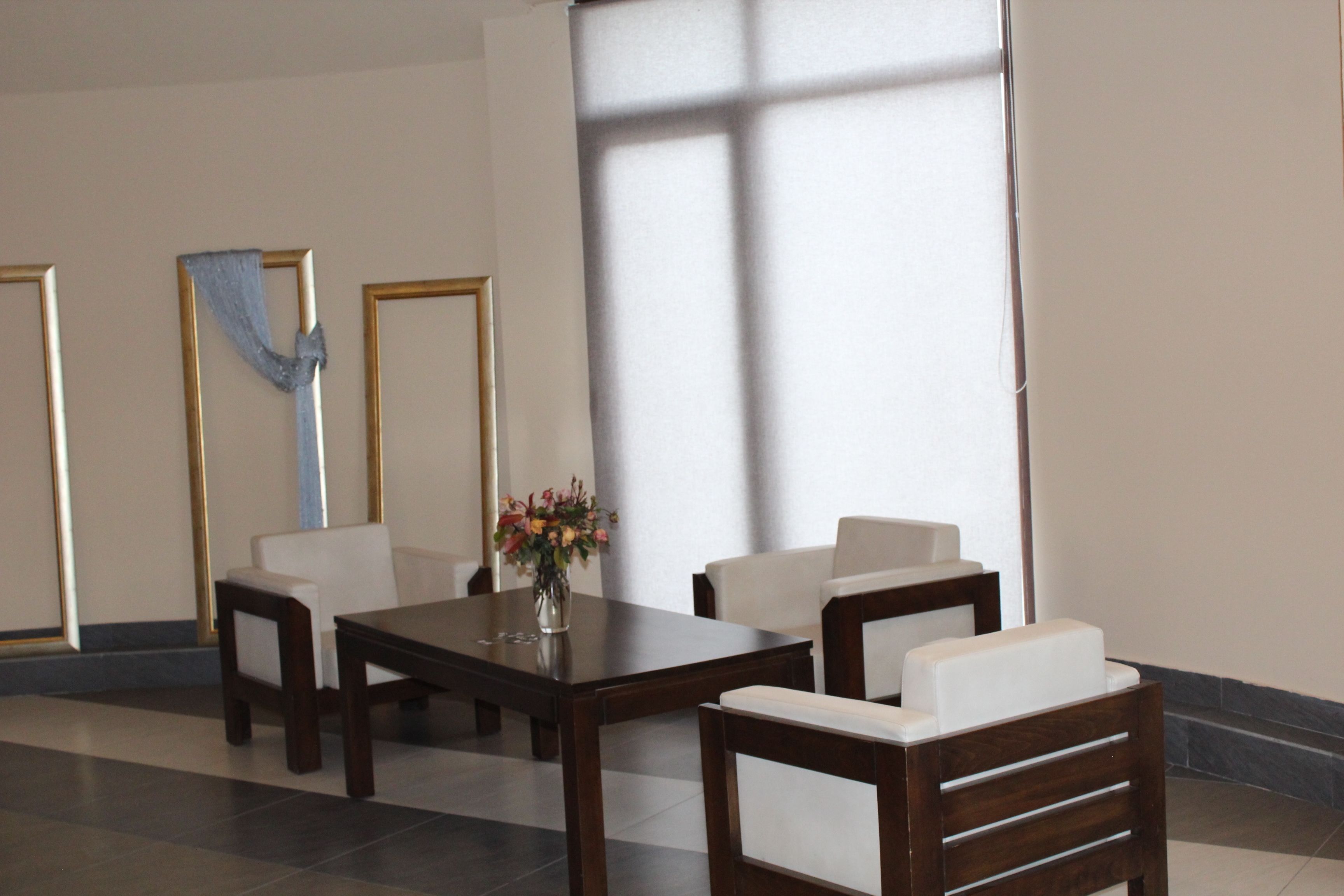A room with a wooden table, two white chairs, and a vase with flowers.