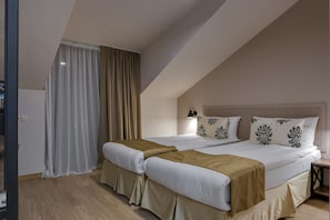 A bedroom with two beds, beige bedding, a wooden floor, and a nightstand with a lamp. - Savaneti (Telavi)
