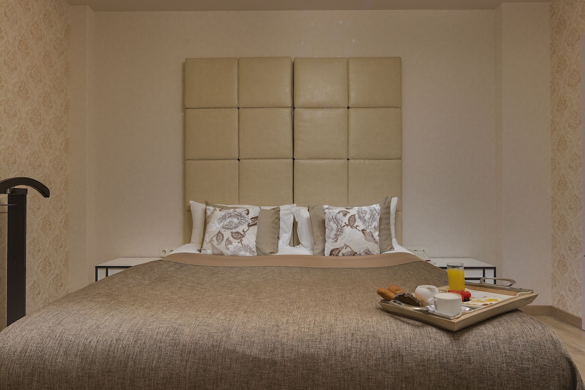 Quarto de hotel com uma cama grande, cabeceira e bandeja com itens de café da manhã.