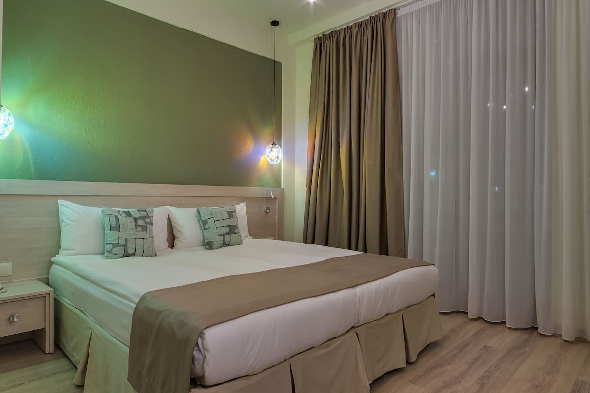 Cama bem arrumada com cabeceira, mesa de cabeceira e abajur.