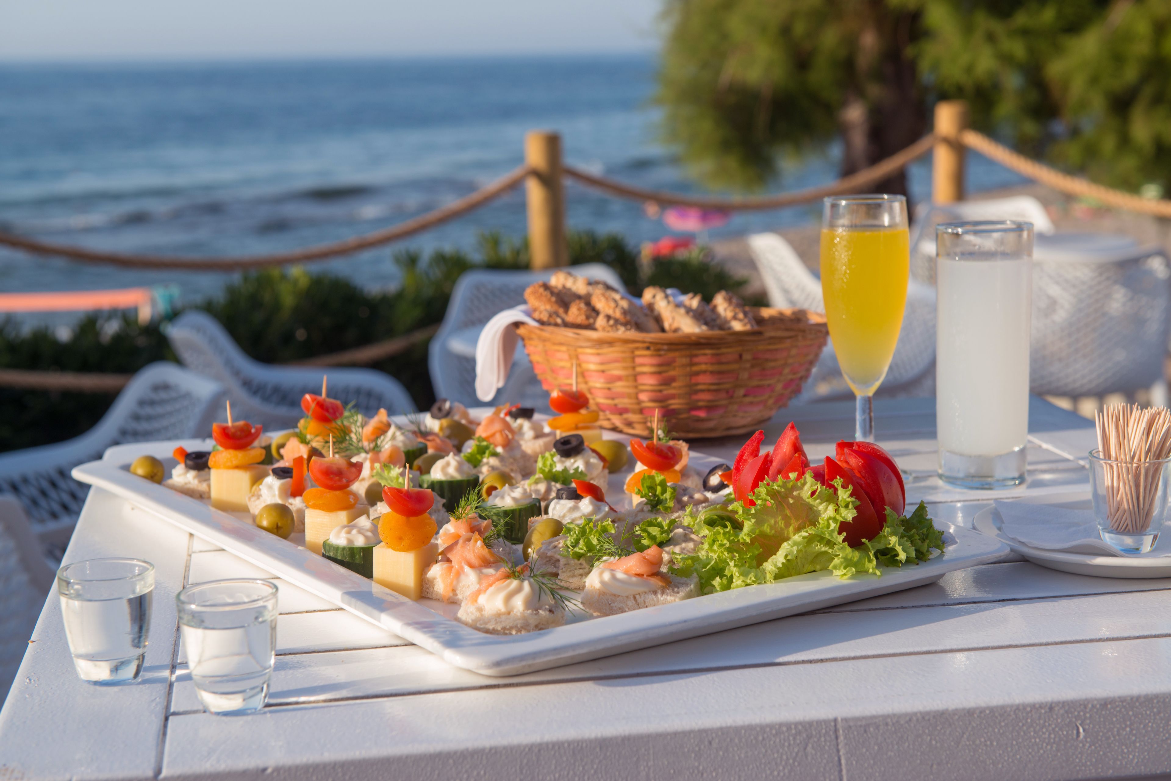Una mesa con diversos aperitivos y bebidas, con vista al mar.