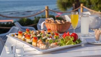 Una mesa con diversos aperitivos y bebidas, con vista al mar.
