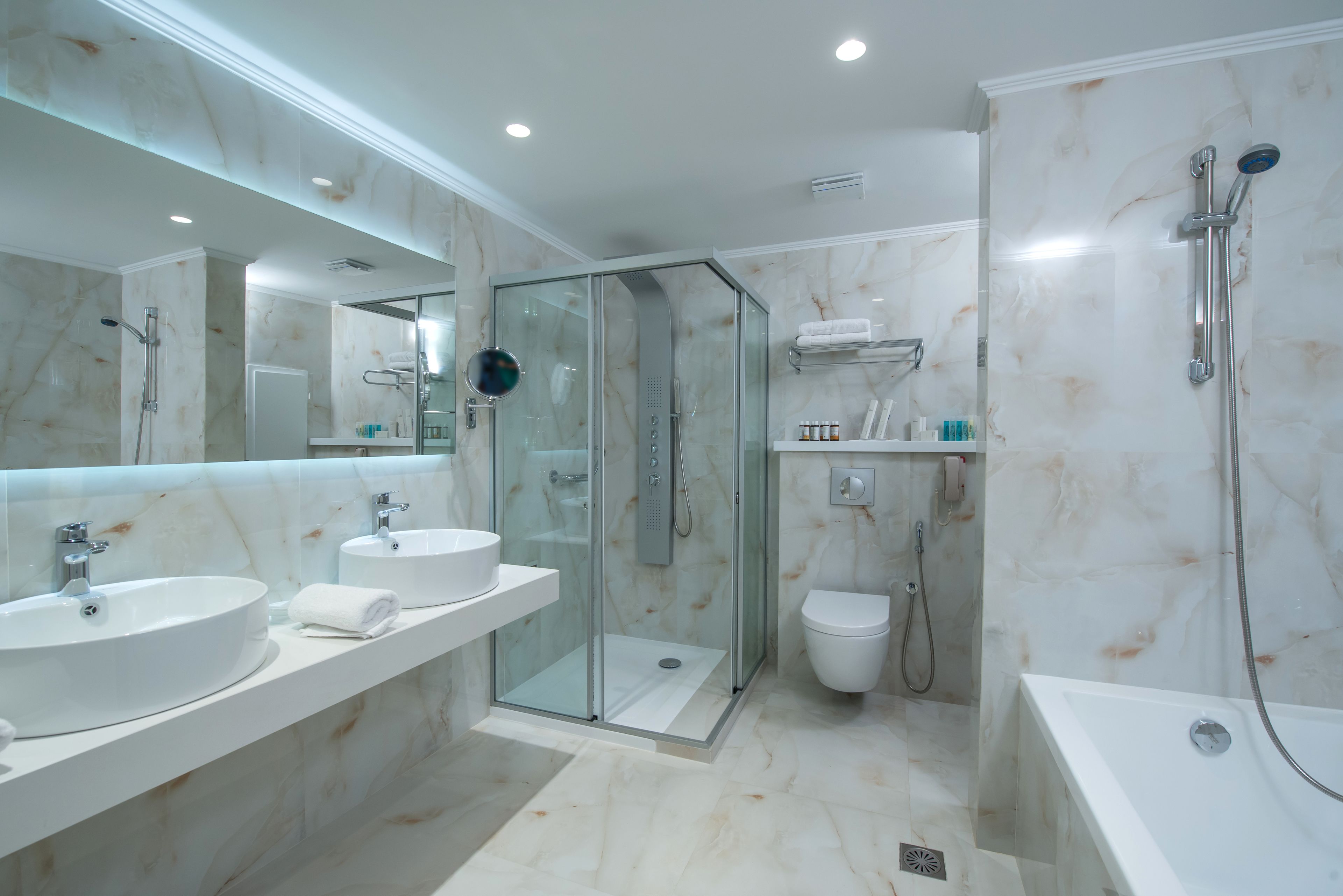 Un baño moderno con dos lavamanos, una ducha con mampara de vidrio, un inodoro y una bañera.