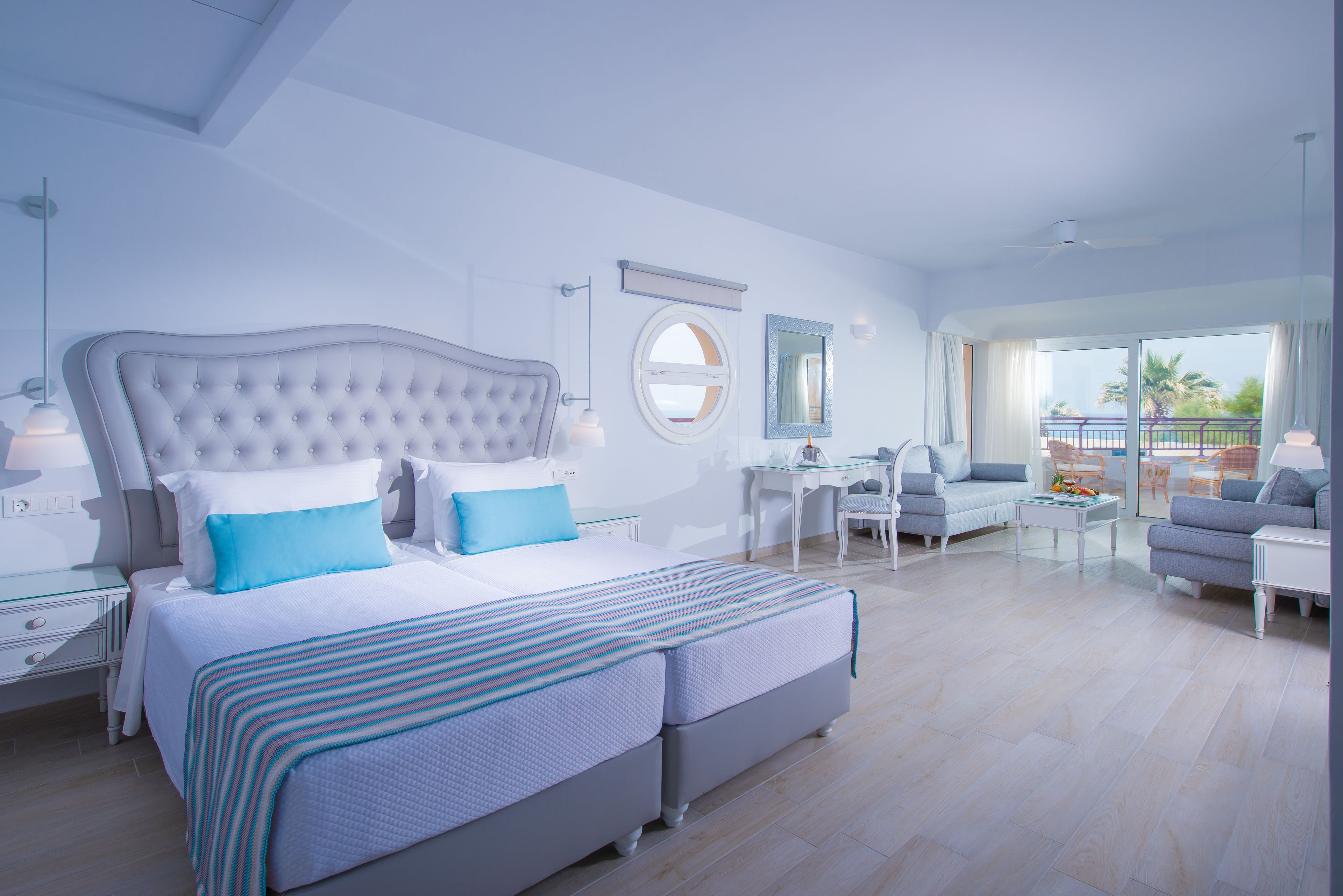A modern bedroom with a large bed, a desk, and a balcony view.