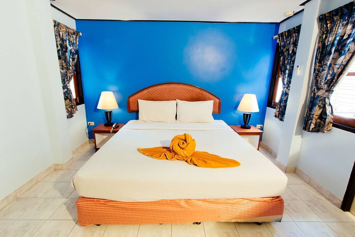Une chambre d’hôtel avec un grand lit, deux tables de chevet avec des lampes et des murs bleus.