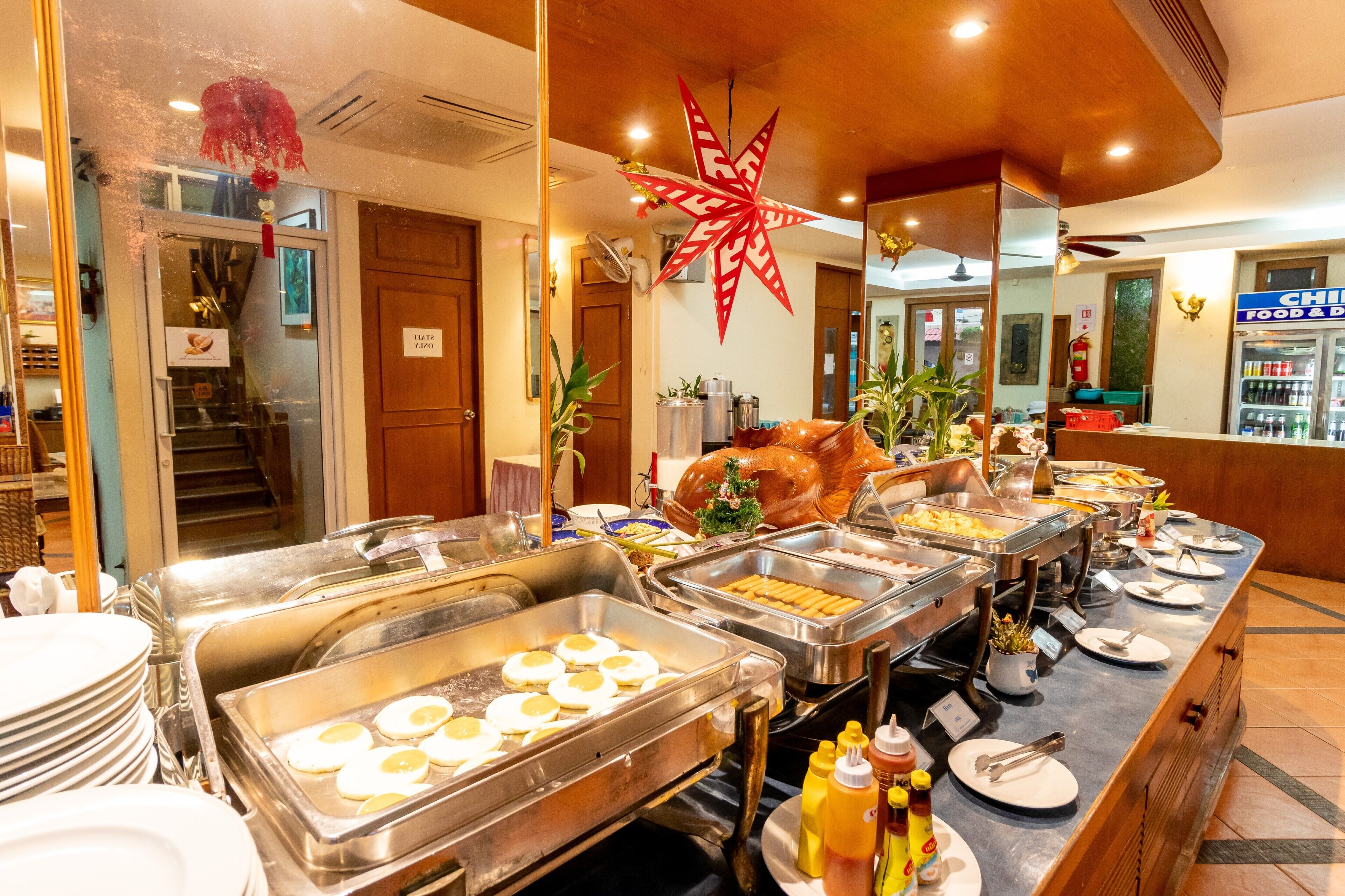 Zona de buffet con diversas opciones de comida, una gran estrella decorativa y un refrigerador al fondo.
