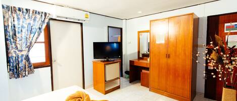 Una habitación de hotel con cama, televisor, armario y escritorio.