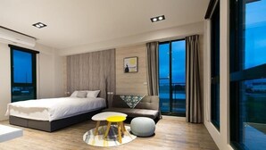 A modern bedroom with a bed, a sofa, a small table, and a round ottoman. - Wei Wei Chu B&B (Zhuangwei)