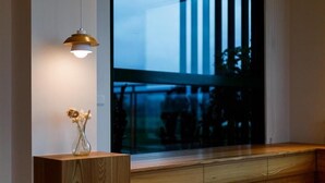 A modern interior with a wooden bench, a vase with flowers, and a pendant light. - Wei Wei Chu B&B (Zhuangwei)