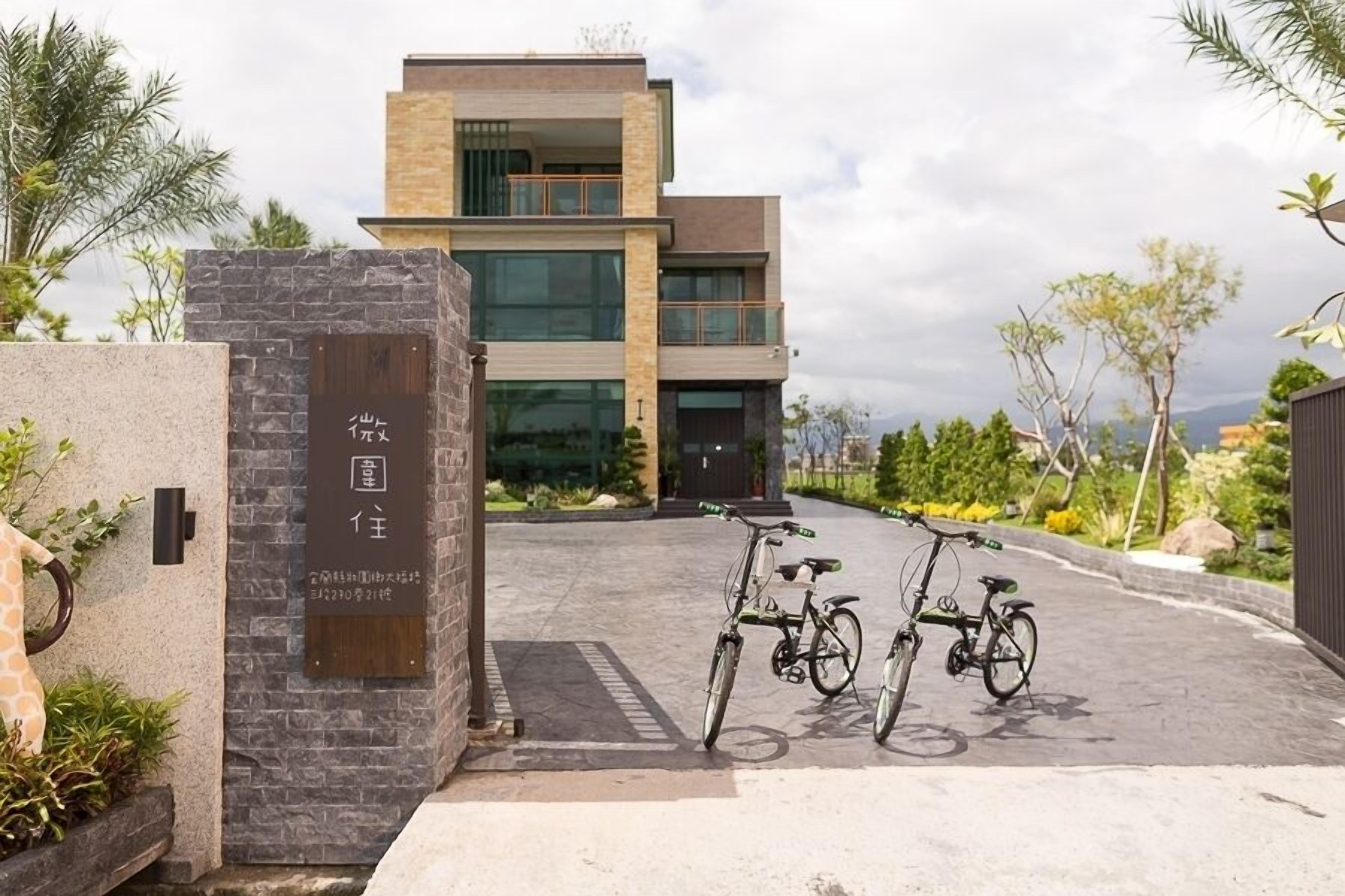 A modern building with a stone facade and a signboard. There are bicycles parked in front.