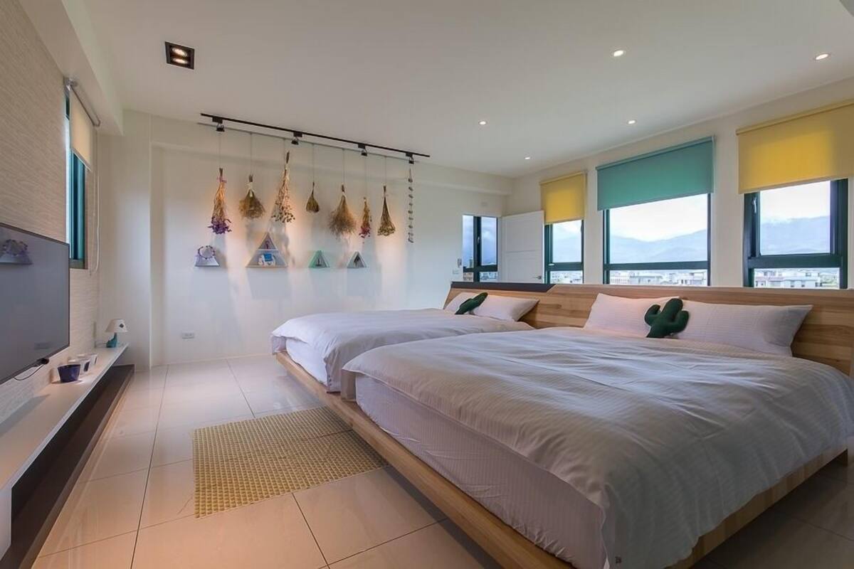 Un dormitorio moderno con dos camas, un televisor y vista a la ciudad.