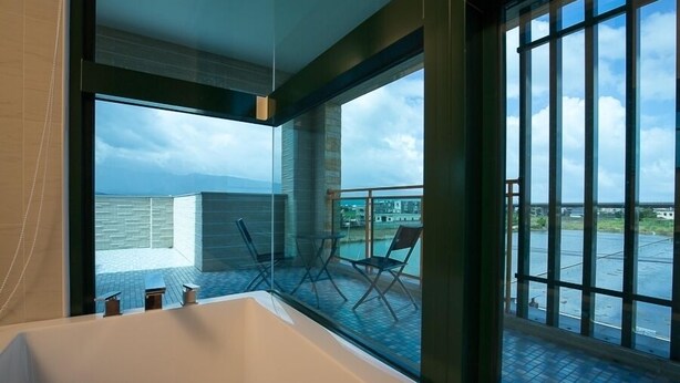 A modern bathroom with a large bathtub, a glass-enclosed shower area, and a view of the cityscape through large windows. - Wei Wei Chu B&B (Zhuangwei)