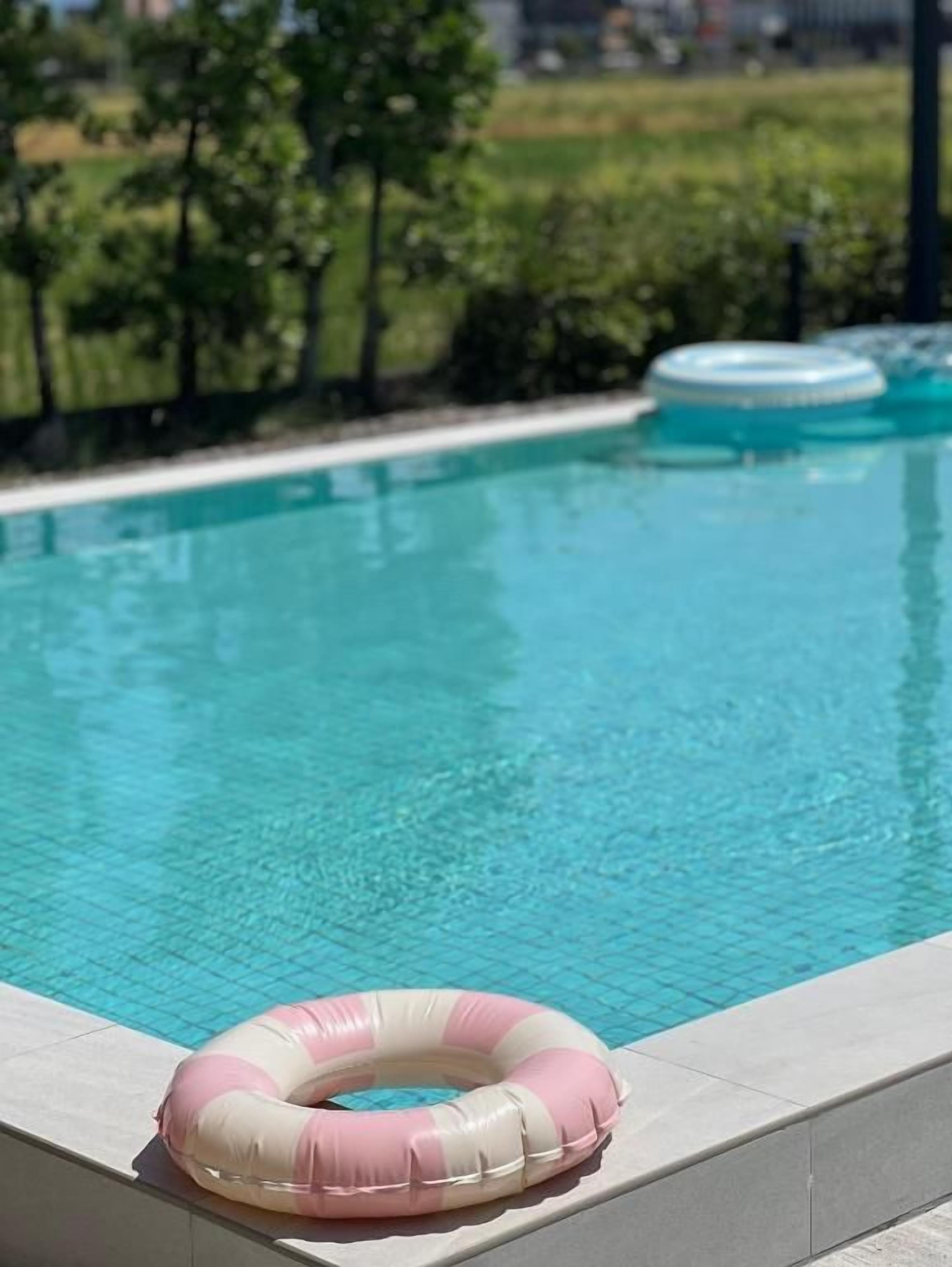 A swimming pool with a pink and white inflatable ring on the edge.