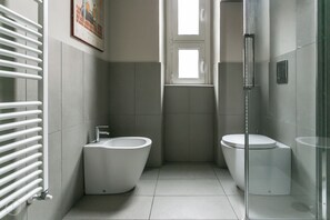 Un baño moderno con un bidé, un inodoro y una cabina de ducha de cristal.