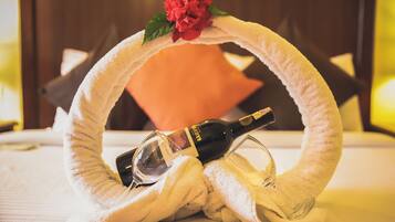 A towel ring with a bottle of wine and a glass, placed on a bed with a pillow.