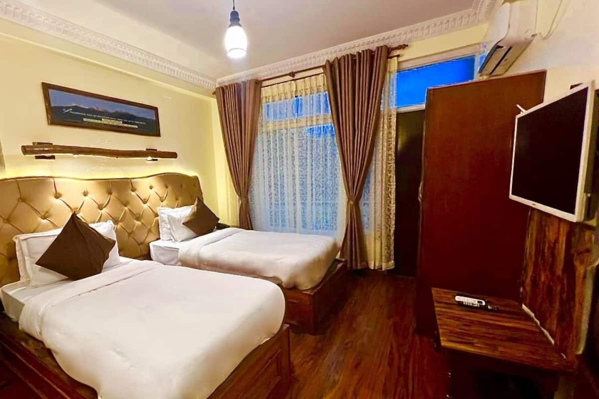 Ein Hotelzimmer mit zwei Betten, einem Fernseher und einem großen Fenster mit Vorhängen.