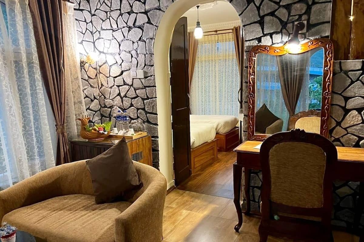 Ein gemütliches Zimmer mit Steinwand, einem Bett, einem Holzstuhl und einem Esstisch.