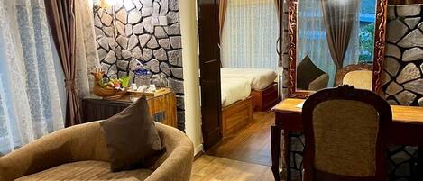 A cozy room with a stone wall, a bed, a wooden chair, and a dining table.
