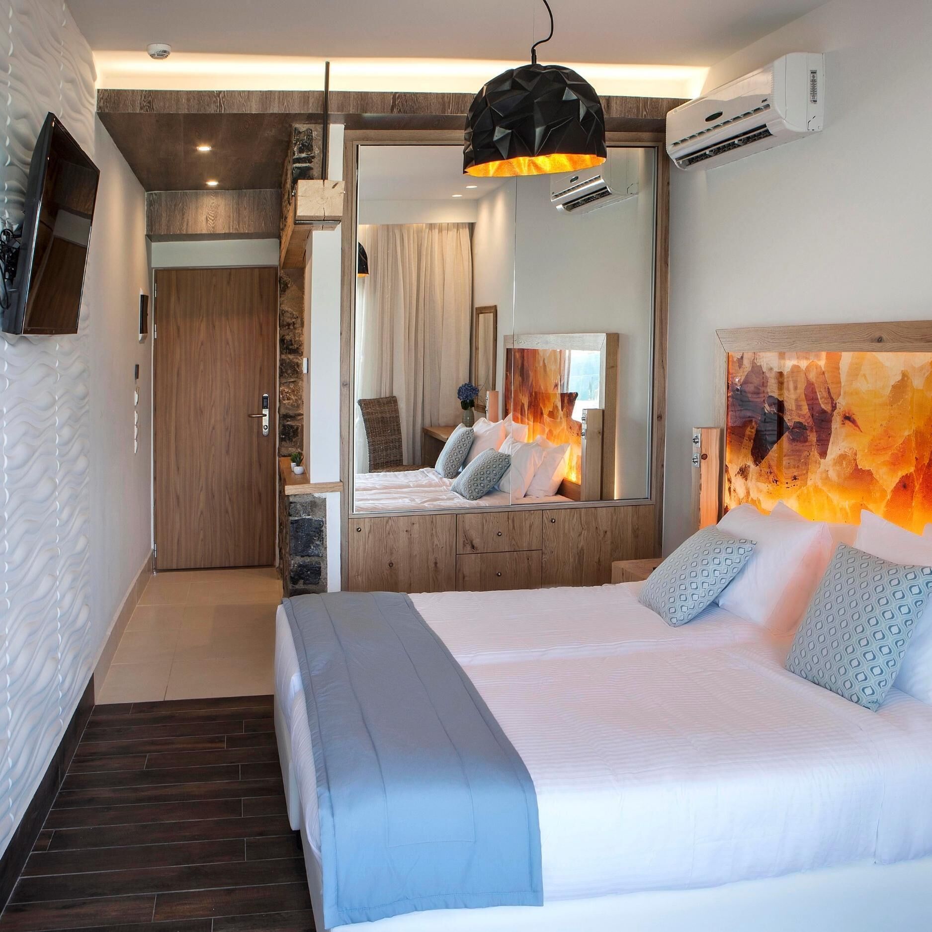 A modern hotel room with a large bed, a mirror, and a unique wall art piece.