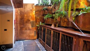 A narrow corridor with a metal wall, a wooden bench, and a small plant. - Italianway - Fiori Chiari (Milan)