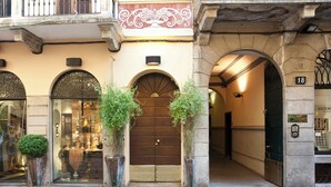 A building facade with arched windows, a wooden door, and a number plaque. - Italianway - Fiori Chiari (Milan)