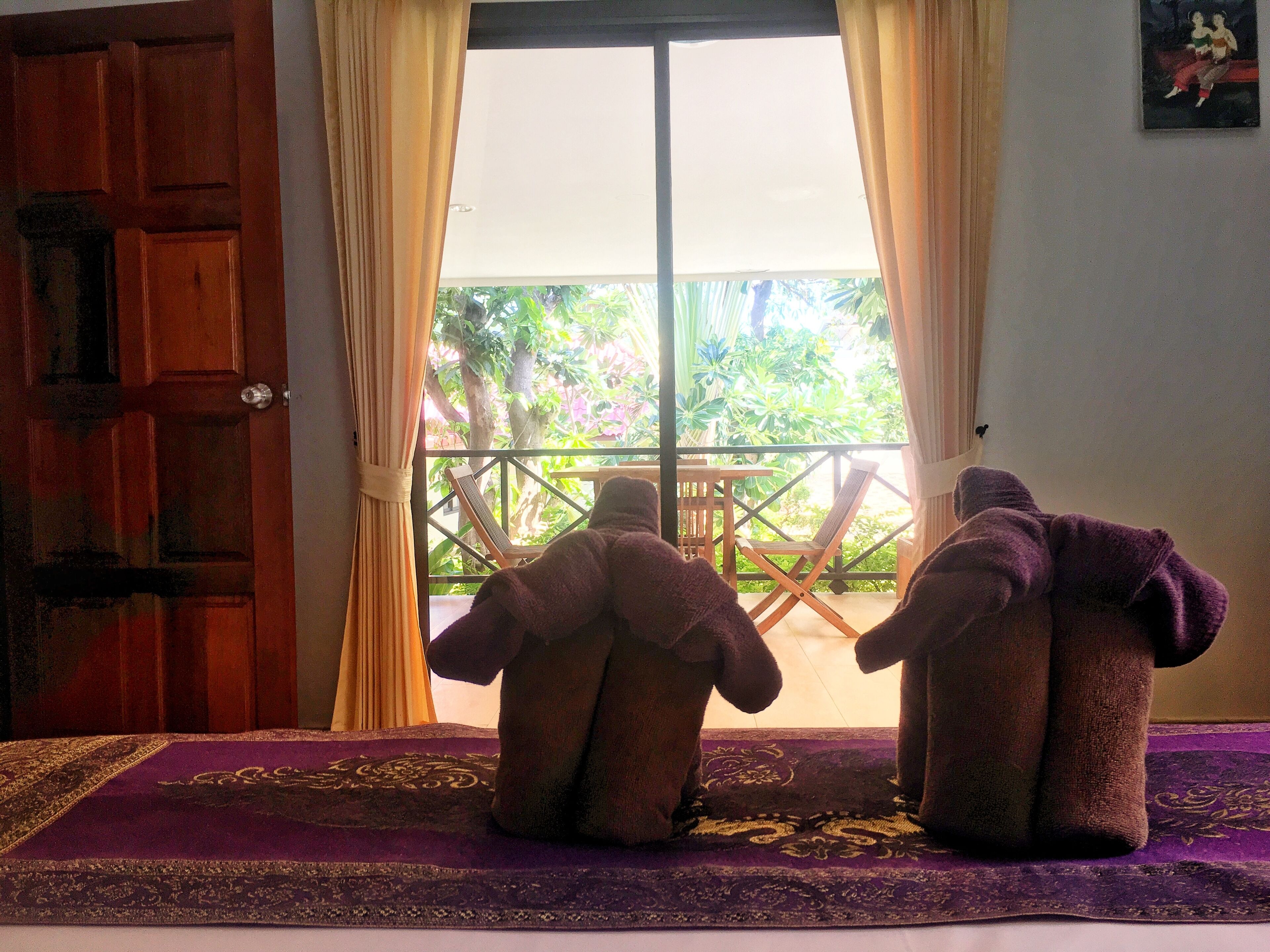 A room with a large window, a wooden door, and a purple carpet.