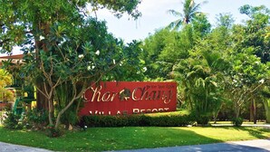 A sign for Chon Ching Villas Resort surrounded by lush greenery and palm trees. - Chor Chang Villa Resort (Koh Samui)