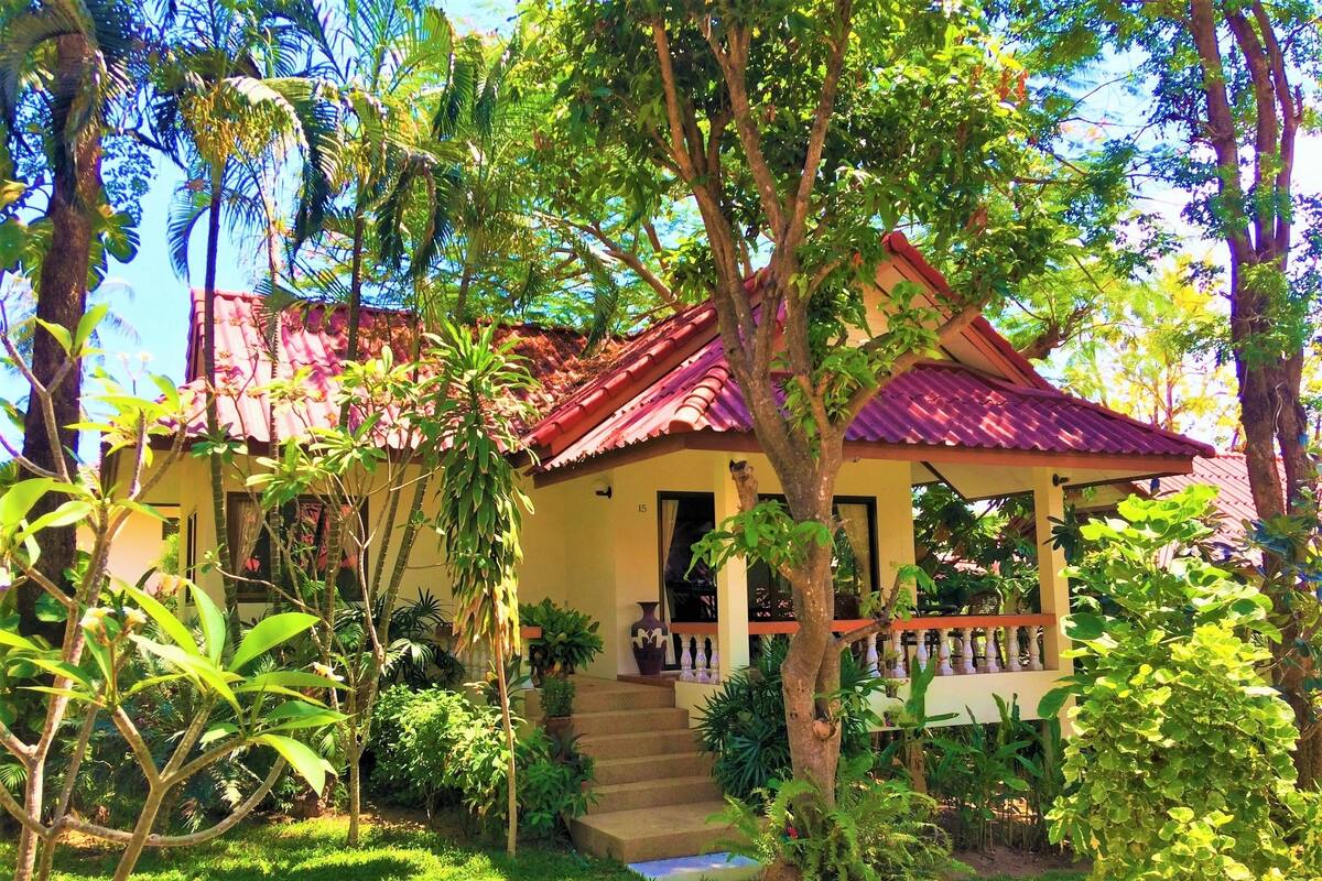 A house with a red roof, surrounded by lush greenery and a well-maintained garden.
