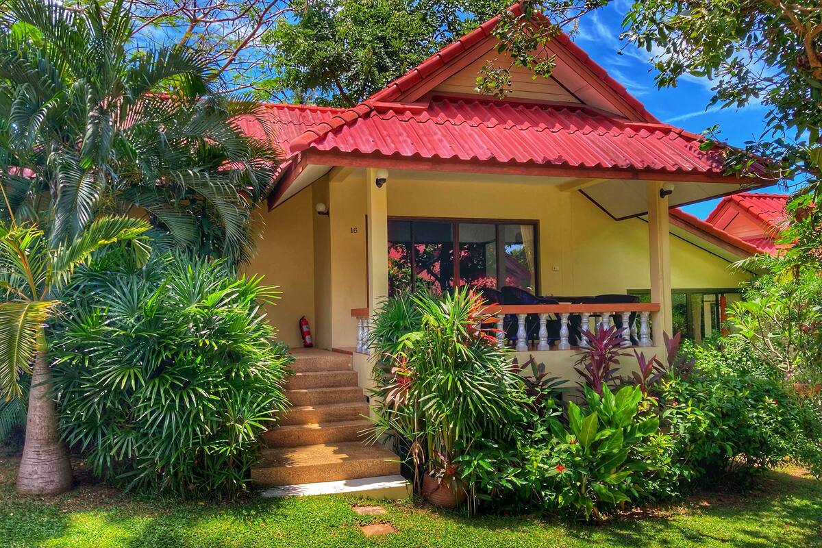 A house with a red roof, a covered porch, and a staircase leading to the entrance.