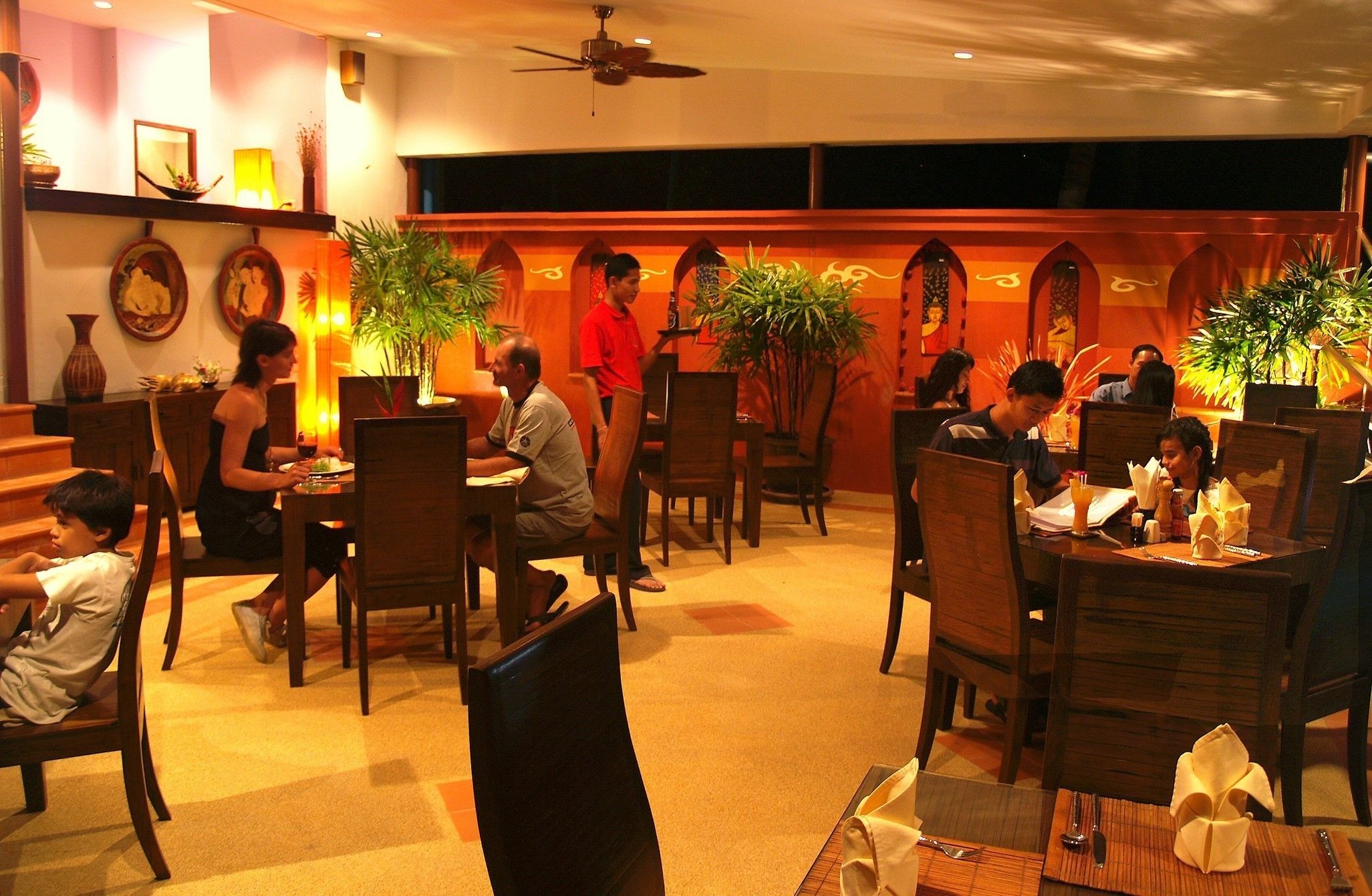 A restaurant with wooden furniture, potted plants, and a warm ambiance.