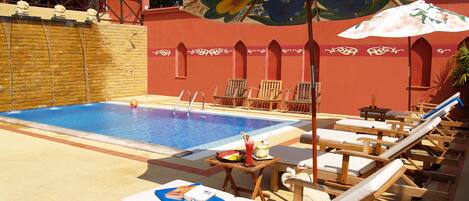 A pool area with lounge chairs and umbrellas.