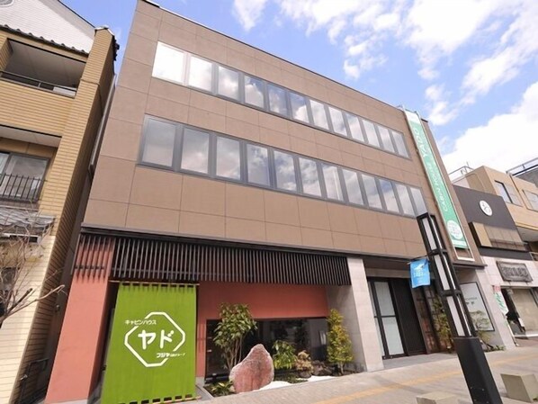 A modern building with a flat roof, large windows, and a green awning with Japanese characters. - Cabinhouse Yado Fujinomiyaten (Fujinomiya)