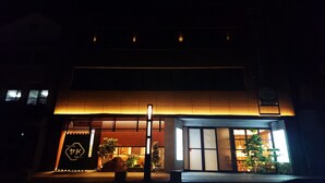 A building with a warm illuminated entrance, a sign with Japanese characters, and a small tree in front. - Cabinhouse Yado Fujinomiyaten (Fujinomiya)