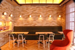A restaurant with brick walls, a green cushioned bench, and wooden tables and chairs. - Cabinhouse Yado Fujinomiyaten (Fujinomiya)