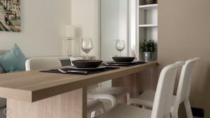 A modern dining area with a wooden table, white chairs, and a potted plant.