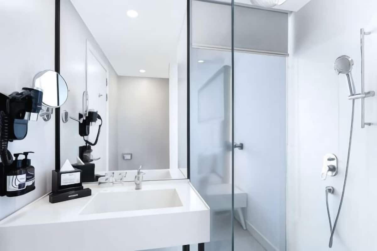 Une salle de bain moderne avec un lavabo blanc, un miroir et une douche en verre.