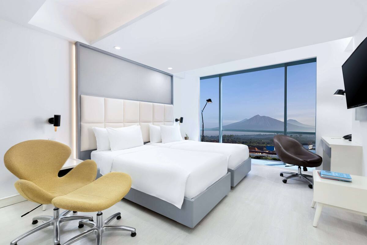 Une chambre d’hôtel moderne avec un grand lit, un bureau, une chaise et une vue sur la montagne.